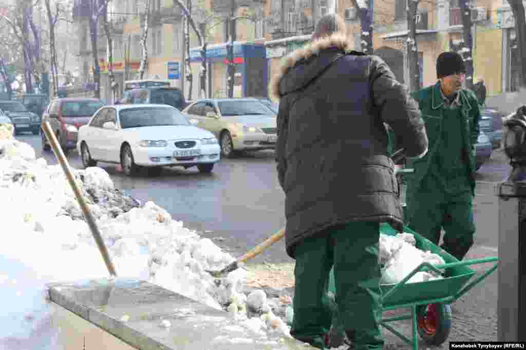 Жол бойын қардан тазалап жүрген жұмысшылар