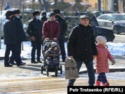 Орталық саябақ жанында тұрған полиция қызметкерлерінің қасынан өтіп жатқан адамдар. Алматы, 28 ақпан 2021 жыл.