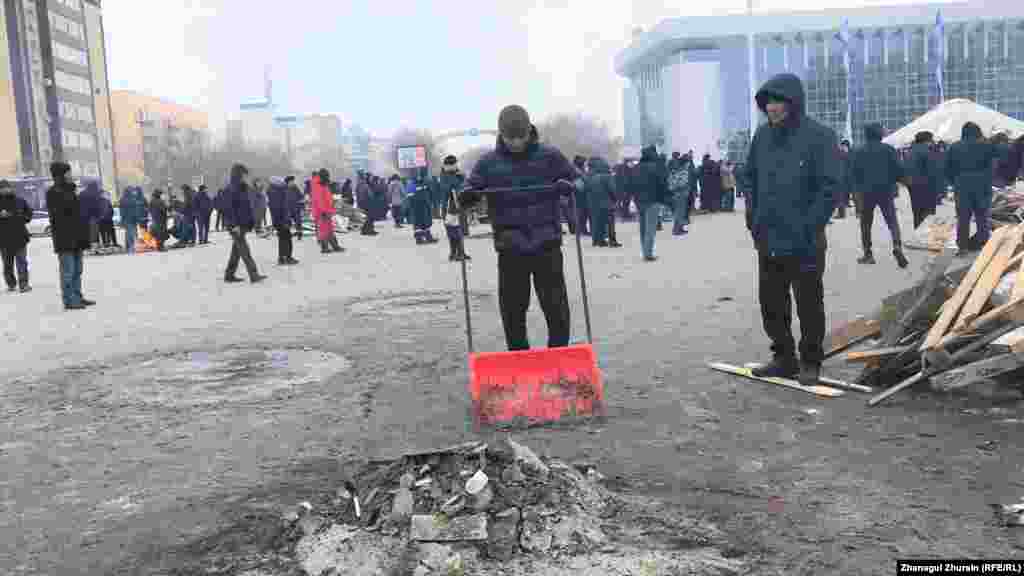 Наразылық акциясы өтіп жатқан алаңды тазалап жүрген адам. Ақтөбе, 6 қаңтар 2022 ж.