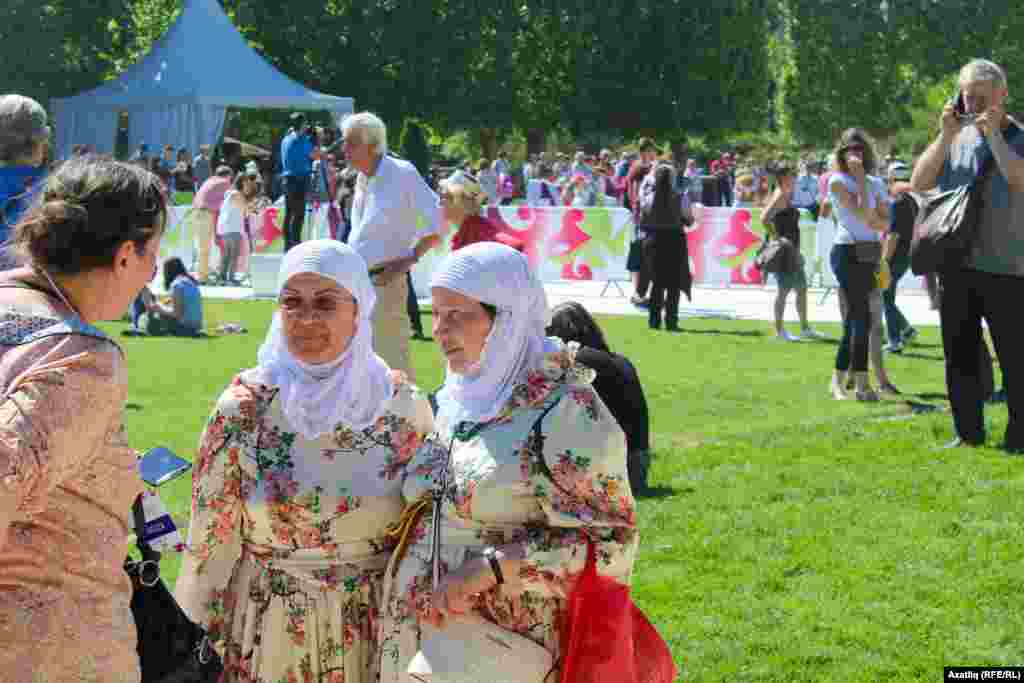 БАҚ өкілі Париждегі сабантойға ұлттық киіммен келген әйелдермен әңгімелесіп тұр.