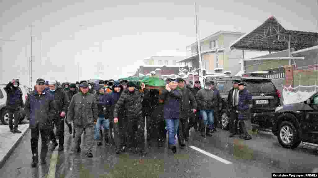 Марқұмның сүйегін көлікке салуға апара жатқан адамдар. &nbsp;